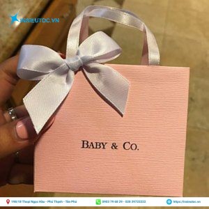 Túi giấy nhỏ xinh màu hồng có quai trắng bắt mắt. Túi giấy đựng quà màu hồng gắn nơ